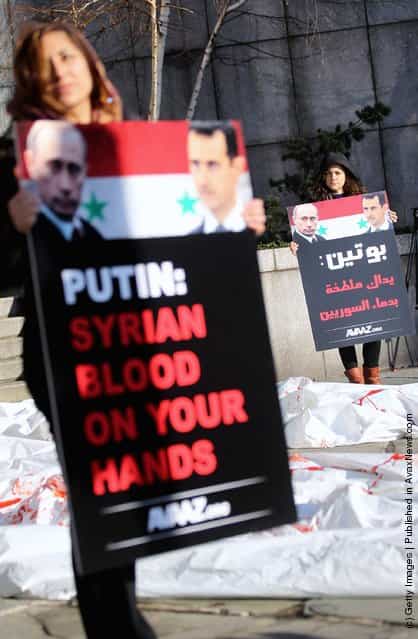 Demonstrators protest against Syrian President Bashar al-Assad and Russian Prime Minister Vladimir Putin next to mock body bags outside United Nations headquarters