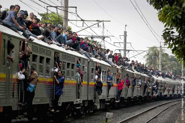 Commuters ride on the roof of a Jakarta state rail train at Cawang train station in Jakarta, Indonesia