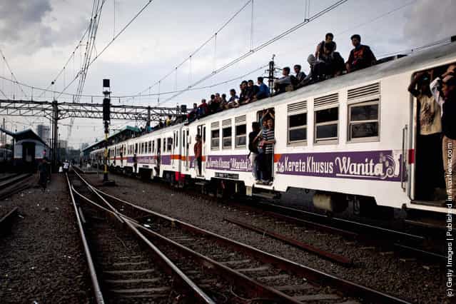 Commuters ride on the roof of a Jakarta state rail train at Cawang train station in Jakarta, Indonesia