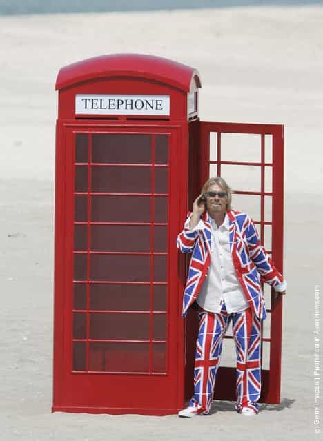 British Entrepreneur and businessman Sir Richard Branson poses next to a phone box during a photocall on a stretch of sand on the man-made island known as United Kingdom in the new development, The World