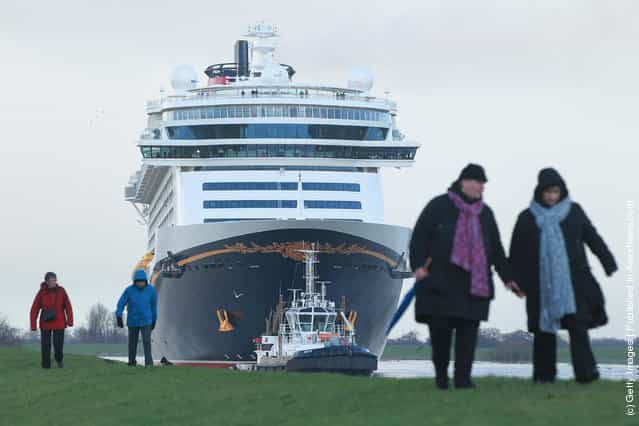 Tugboats haul the [Disney Fantasy] cruise ship backwards down Ems river after the ship departed from the Meyer Werft shipyards