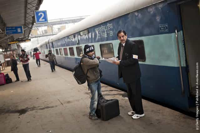 A passenger checks his seating on the Amritsar bound train, as he receives help from a conductor at the Nizamuddin Railway Station in New Delhi, India