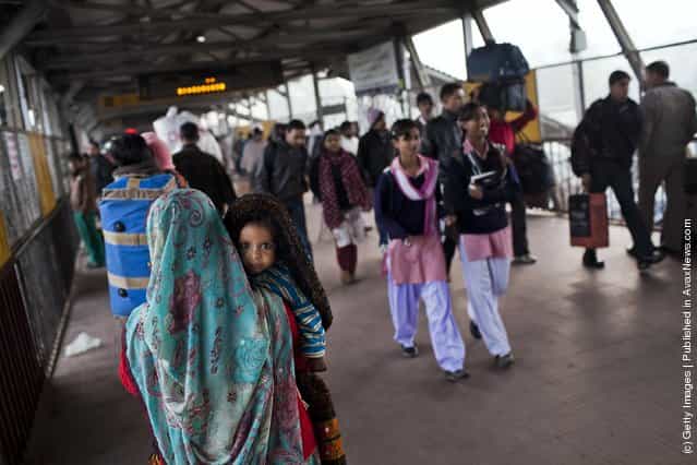 A woman carries a baby through Nizamuddin Railway Station in New Delhi, India