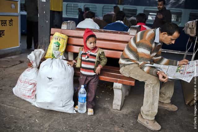 A boy waits with his families belongings prior to boarding a train at the Nizamuddin Railway Station in New Delhi, India
