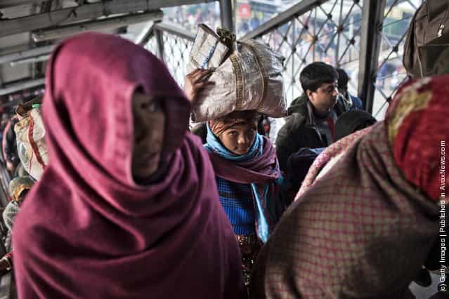 People carry their belongings after alighting from a train at the Nizamuddin Railway Station in New Delhi, India