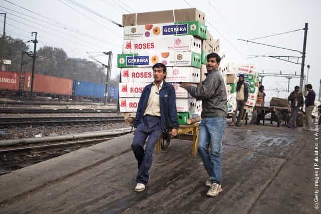 Workers move the morning delivery of flowers from a train at the Nizamuddin Railway Station in New Delhi, India