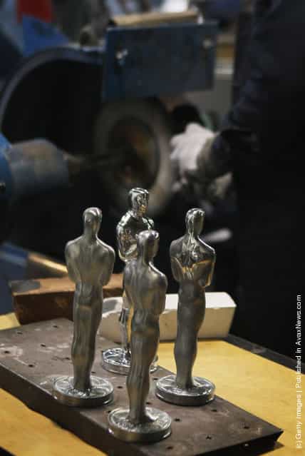 A worker polishes Oscar statuettes at R.S. Owens & Company