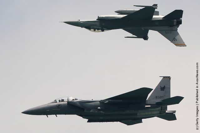 An F-15SG (bottom) and the F-16C fighters from the Republic of Singapore Air Force perform during the opening day of the Singapore Airshow 2012 at the Changi Exhibition Cenre