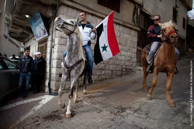 A Druze man, on horseback, waves the Syrian flag during a rally in the village of Majdel Shams, near the border between Israel and Syria