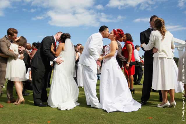 (L-R) Jonah Klemm-Toole kisses his new wife, Elena Pizano, Kenny Dornhoefer kisses his new wife, Jaya Ganaishalm and Manuel Fuentes kisses his new wife, Monika Juarbe after being wed during a group Valentine's day wedding at the National Croquet Center