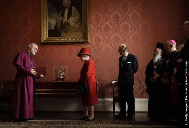 Britain's Queen Elizabeth II is shown the Ampulla and Coronation Spoon, which was used at her Coronation in 1953, by the Archbishop of Canterbury Rowan Williams as her husband Prince Philip, Duke of Edinburgh, and other Christian guests watch, during a multi-faith reception at Lambeth Palace