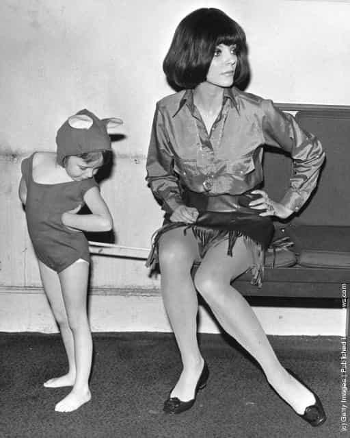 1968: Actress Joan Collins unwittingly sits on the tail of her five-year old daughter Taras mouse suit during rehearsals for Airs and Graces the childrens matinee in aid of the Forces Help Society and Lord Roberts Workshops, at the Scala Theatre