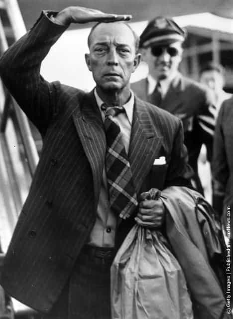 1947: Clutching a large paper bag and shading his eyes as he peers ahead, comic actor of the silent screen, Buster Keaton (1885 - 1966) arriving at Paris airport