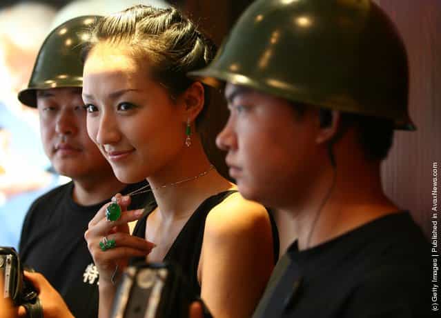 A model escorted by security guards, displays a emerald pendant worth about 28 million yuan (about USD 3.71 million), at a jewelry shop