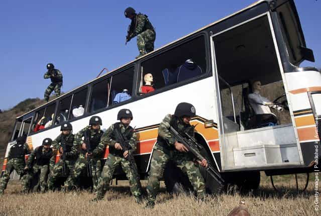 Chinese armed police officers surround a coach during a simulated terrorist hijacking as part of an anti-terror drill by the Shanghai Armed Police Corps