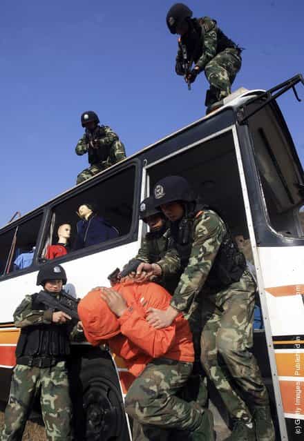 Chinese armed police officers surround a coach during a simulated terrorist hijacking as part of an anti-terror drill by the Shanghai Armed Police Corps