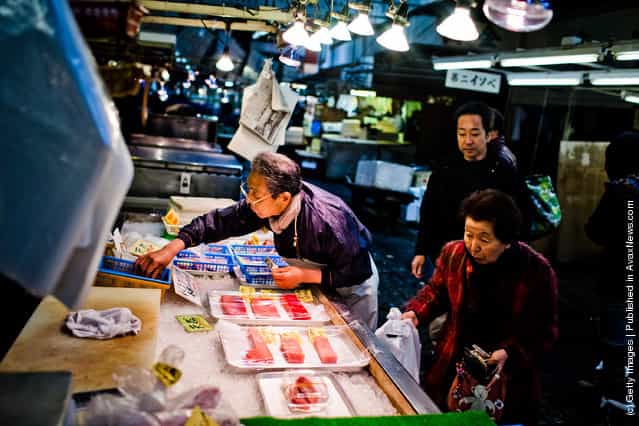 A worker looks for change as he serves a customer at the Tsukiji fish market
