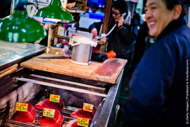 A shopkeeper smiles as he speaks with customers at the Tsukiji fish market