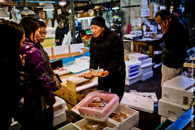 A man displays fish to customers at the Tsukiji fish market
