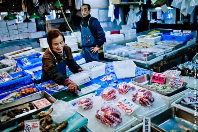 A woman starts to pack away seafood at the end of trade at the Tsukiji fish market