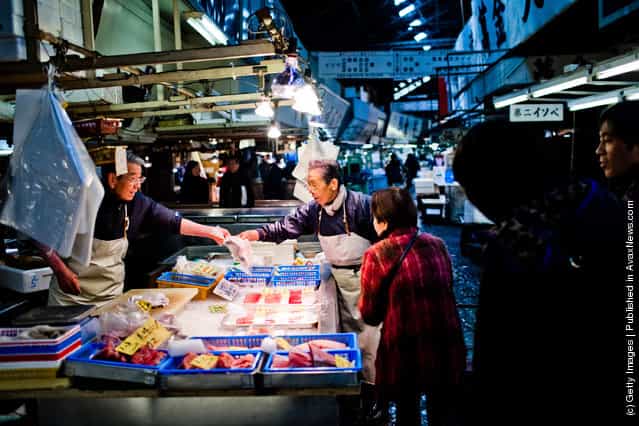 Workers point to a fish as they serve a customer at the Tsukiji fish market