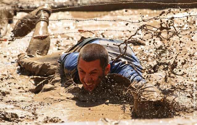Competitors crawls through a mud pit under barbed wire as he competes in The Tough Bloke Challenge in Melbourne, Australia