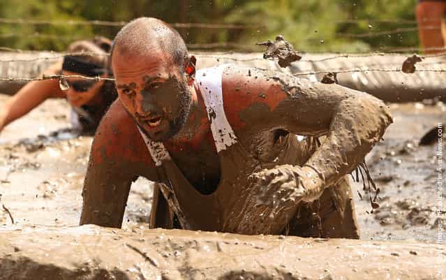 Joe Armanta crawls through a mud pit under low slung barbed wire as he competes in The Tough Bloke Challenge