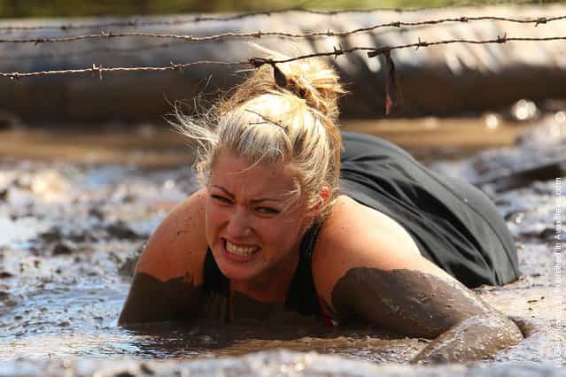  A competitor crawls through a mud pit under low slung barbed wire as she competes in The Tough Bloke Challenge