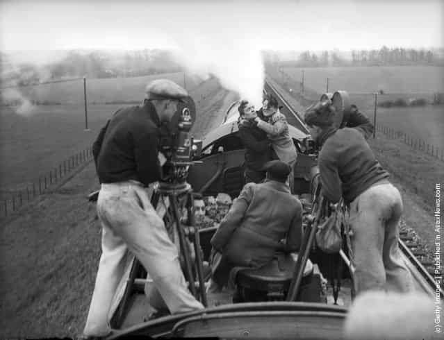 1934: Actors and cameramen balancing atop the famous Scots express train Aberdonian as it steams through Hertfordshire. The train has been loaned to British Lion Films by the LNER for a fight scene in their latest production Night Mail
