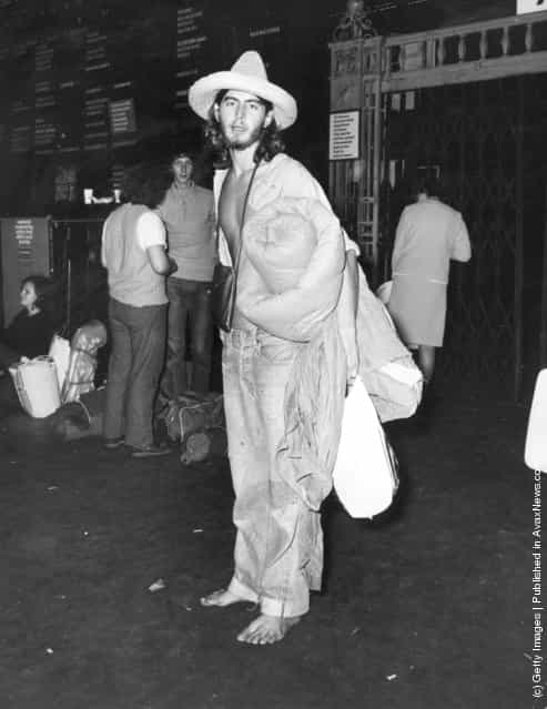 1970: A shoeless hippy at Waterloo Railway Station, London, waiting for a train to the Isle of Wight before the start of the Isle of Wight festival