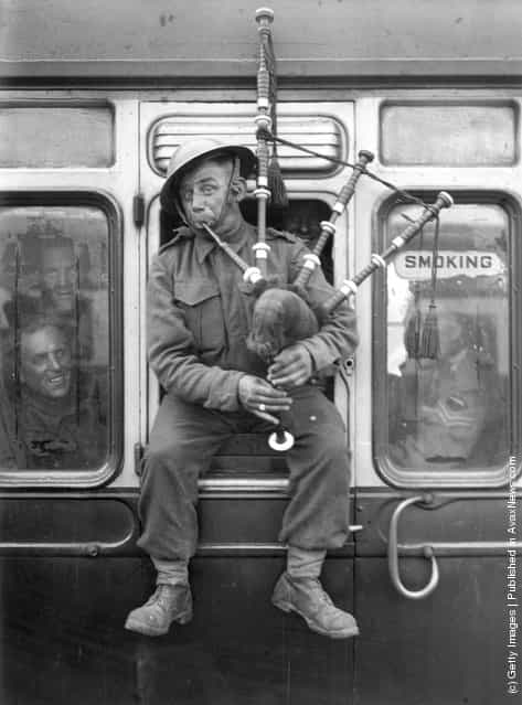 1940: Back in England, one of the British soldiers that continue to return in their thousands from Northern France, belies any mood of defeat with some high spirited piping on a train