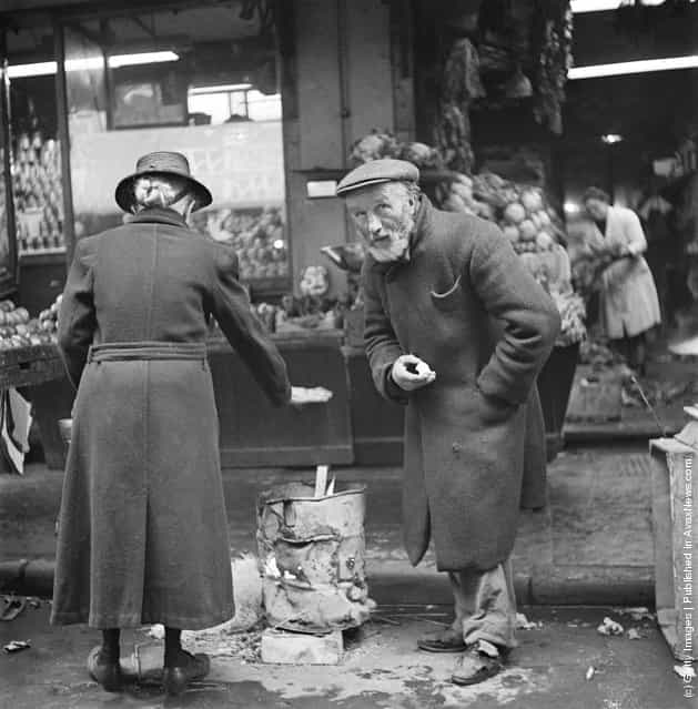 Two people warm themselves at a brazier on a street in the Soho area of London, 1947