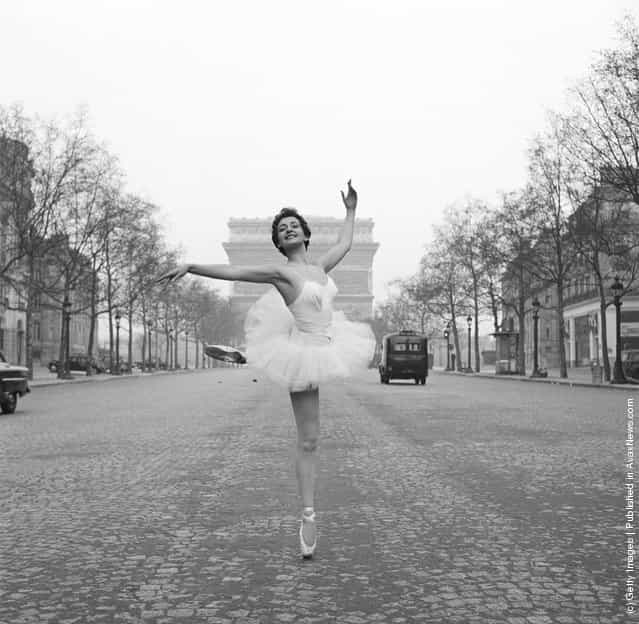 Ballerina Christianne Gaulthier, a dancer at the Moulin Rouge, fulfils a lifelong dream - to dance through the deserted streets of Paris at the crack of dawn, 1955. Here she assumes a classic ballet position on the Champs Elysees