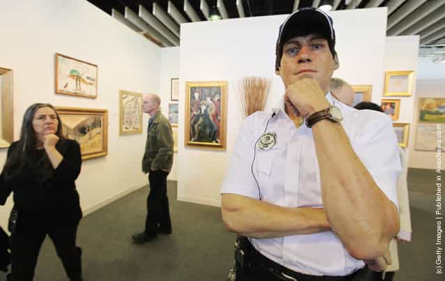 A visitor walks past the life-size sculpture Security Guard by Marc Sijan at The Armory Show, New Yorks annual international art fair, at Piers 92 and 94 on March 9, 2012 in New York City