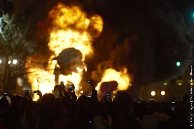 The crowd takes pictures with mobile phones while a combustible Ninot caricatures burns in the background during the last day of the Fallas festival on March 19, 2012 in Valencia