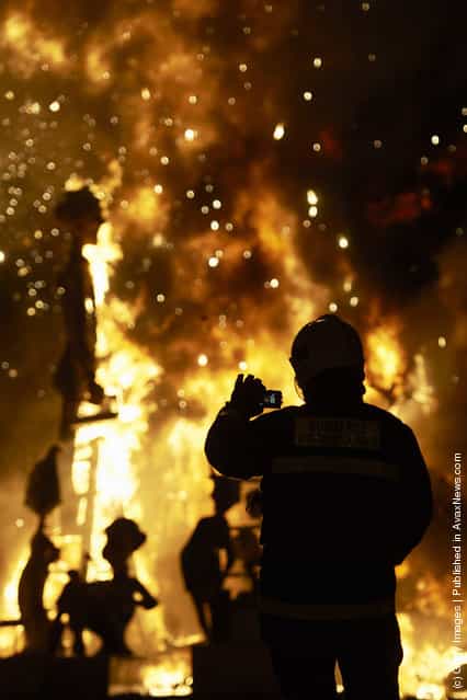 A fireman takes a picture while a combustible Ninot caricatures burn during the last day of the Fallas festival on March 19, 2012 in Valencia, Spain