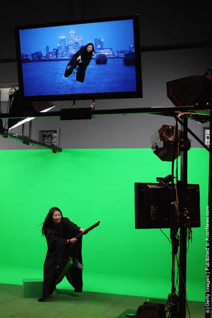 A girl rides a broomstick in front of a green screen at the new Harry Potter Studio Tour at Warner Brothers Leavesden Studios