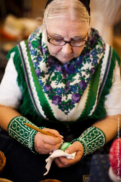 Ute Zschieschang from the village Bergen, wearing a traditional Lusatian sorbian folk dress, paints an Easter egg in traditional Sorbian motives at the annual Easter egg market