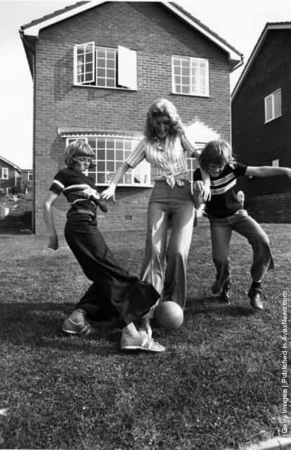 1975: English singer and comedienne Marti Caine playing football with her sons