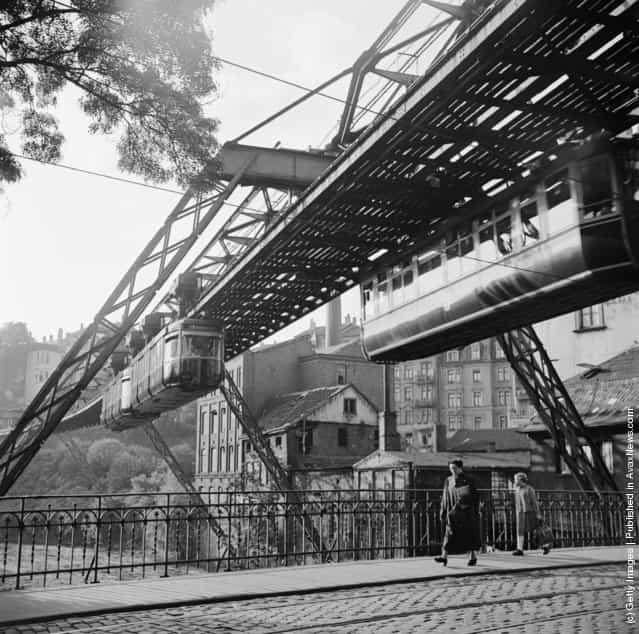 1956: A hanging monorail train moves along the seven mile Wuppertal Monorail System in Germany, just above the stream of traffic