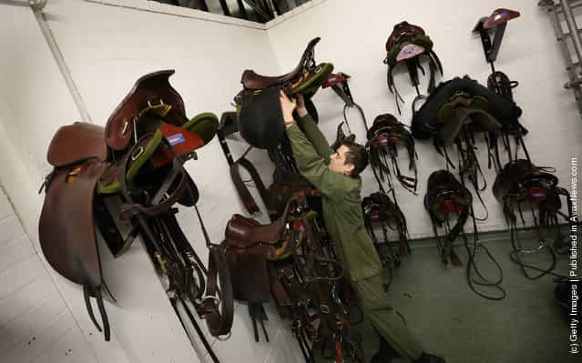 Trooper Marc Goodwin of The Household Cavalry Mounted Regiment (HCMR) lifts a saddle down from the wall in the tack room at Hyde Park Barracks