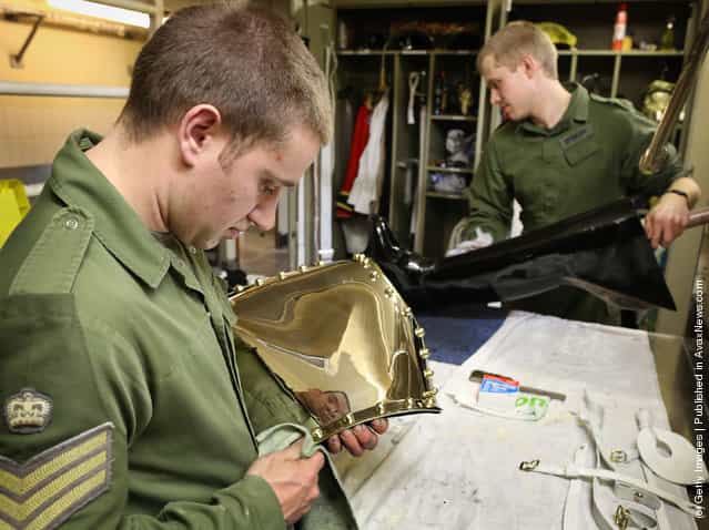 Lance Corporal of Horse Jeffrey Brown (L) polishes his ceremonial breast plate, known as a Cuirass, as his colleague Trooper Edward Spencer polishes one of his riding boots at The Household Cavalry Mounted Regiment (HCMR) at Hyde Park Barracks