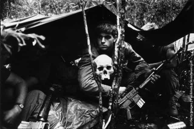 A human skull keeps watch over US soldiers encamped in the Vietnamese jungle during the Vietnam War, 1968