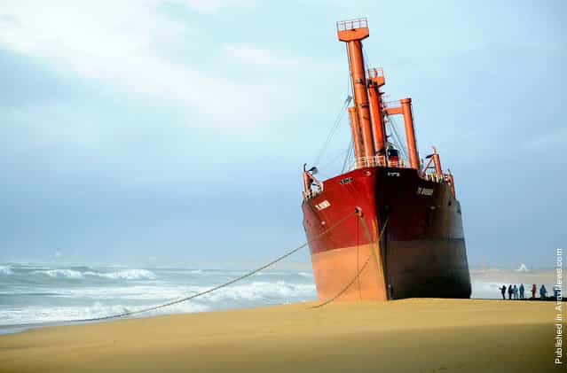 Rescue workers stand next to TK Bremen cargo ship which ran aground during a powerful storm, spilling oil off the coast of Frances northwestern region of Brittany as it lies stranded on Kerminihy beach in Erdeven, on December 16, 2011