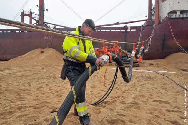 An employee of Dutch company SMIT fixes a pipe during oil pumping operations on the TK Bremen, on December 19, 2011