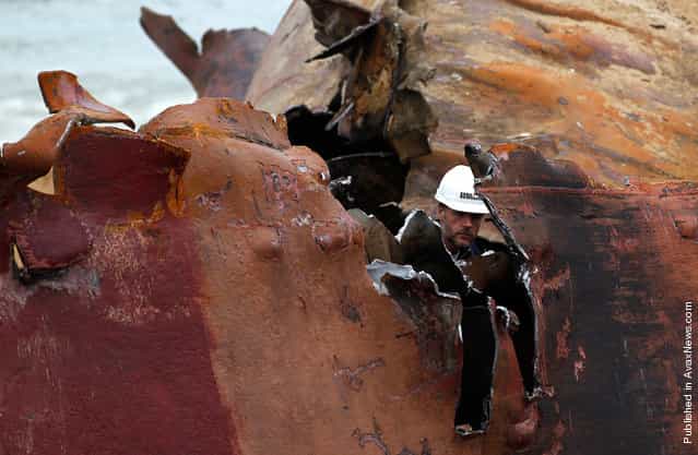 A workman cuts the hull of the TK Bremen into pieces on Kerminihy beach, on January 23, 2012
