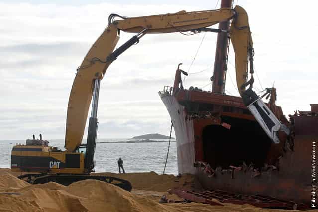A hydraulic shear cuts apart the hull, dismantling the TK Bremen on Kerminihy beach, on January 7, 2012