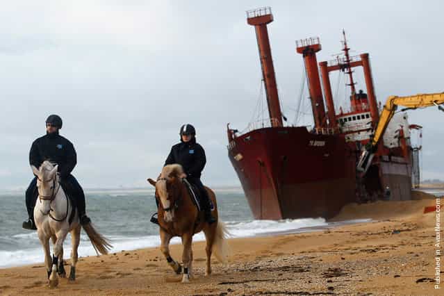 Security officers patrol the beach as a crane dismantles the TK Bremen in western France, on January 7, 2012