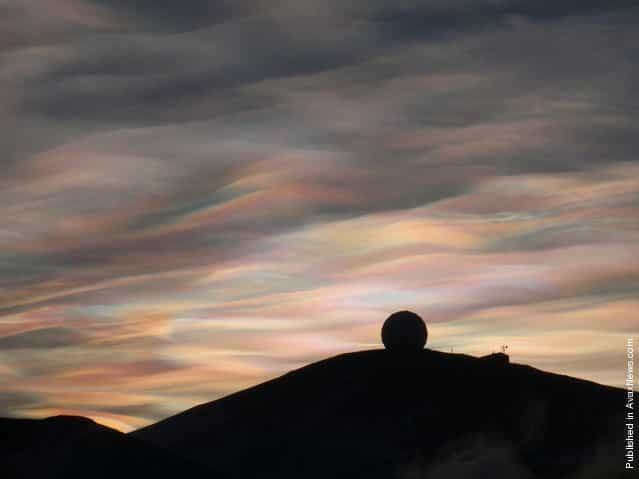 Nacreous Clouds over the NASA Radome (a weatherproof structure housing a 10 meter antenna inside). Nacreous clouds (or Polar stratospheric clouds) form high in the dry stratosphere, catching sunlight well after dusk, displaying brilliant colors