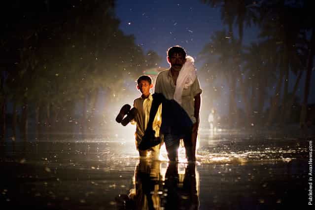 A man and a boy, displaced by floods, walk through flood waters